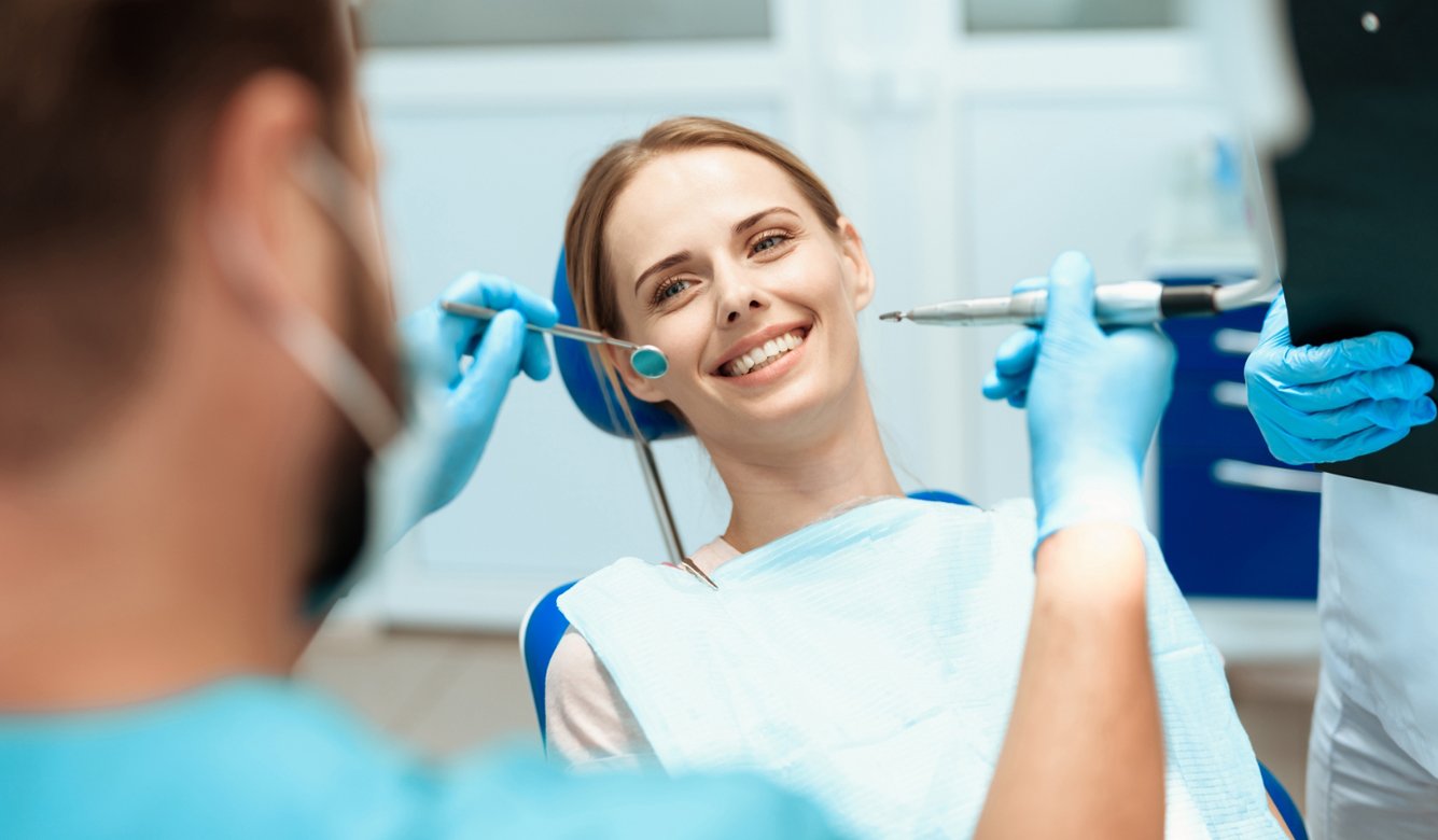 woman-sits-dental-chair-doctors-bowed-her